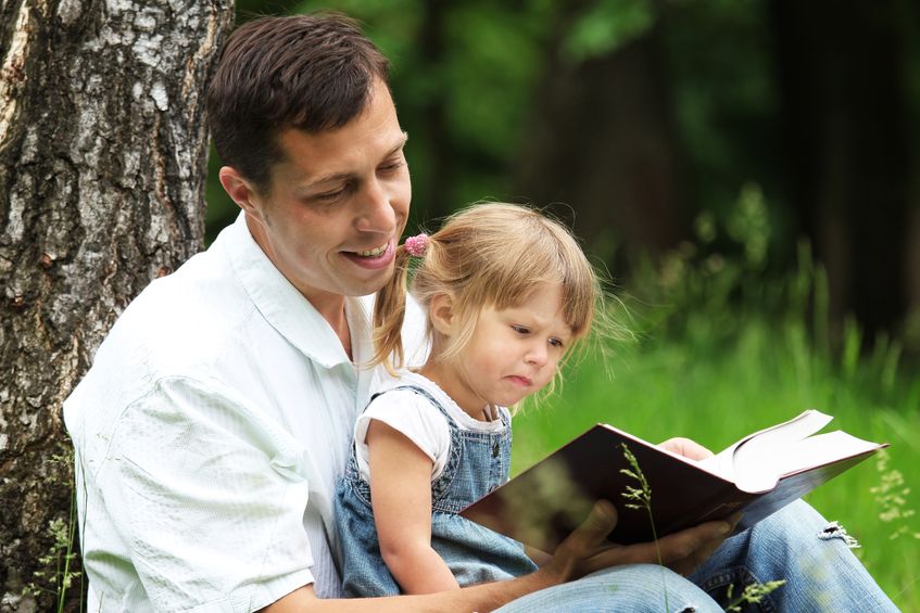 father reading a book to his daughter
